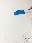 Blaue Farbe wird auf ein Papierherz aufgetragen