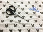 Schere auf weißem Stoff mit Mickey Mouse Muster