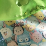 Grüner Stoff wird auf TsumTsum Stoff festgesteckt