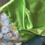 Grüner Stoff ist mit Stecknadeln am TsumTsum Stoff befestigt