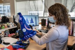 Cast Member im Disneyland Paris Merch Office hält einen Mickey Mouse Zaubererhut in Händen
