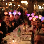 Medienvertreter an einer festlichen Tafel, alle tragen Lightears auf dem Kopf