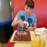 Eine junge Frau beim Anschneiden der Schokoladentorte zum Geburtstag