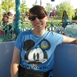 Eine junge Frau mit hellblauem Mixchey Mouse T-shirt trägt eine Sonnenbrille