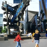 Trümmerteile eines hölzernen Schiffswrack, darauf Schilder mit der Aufschrift Key West Restaurant und ein kopfüber aufgehängter Hai