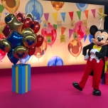 Mickey Mouse posiert mit Geschenken und Luftballons