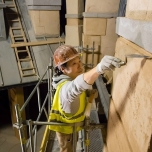 Ein Bauarbeiter mit Warnweste und Helm verputzt eine Wand
