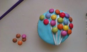 Smarties und Fondant werden auf dem Cupcake angebracht