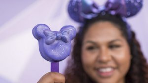 eine Frau hält einen lilafarbenen Cake Pop in der Hand