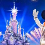 Mickey Mouse in Frack und Zylinder vor dem Schloss mit Feuerwerk