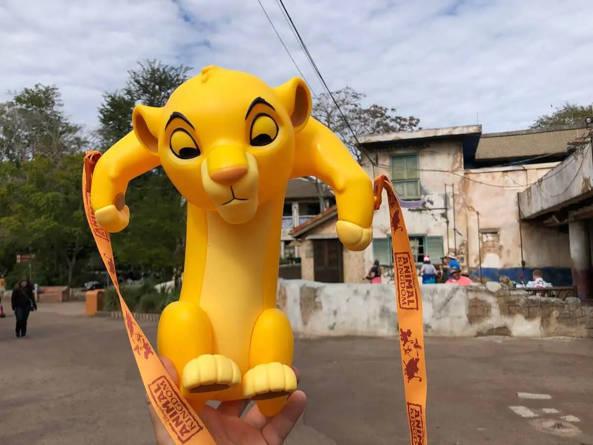 Simba Popcornbecher Eine Hand hält einen Popcorneimer in Form von Simba in die Höhe