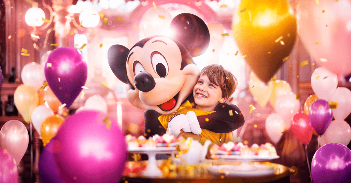 Mickey Mouse Signature Experience Mickey feiert mit einem Kind, umgeben von Luftballons und Konfetti