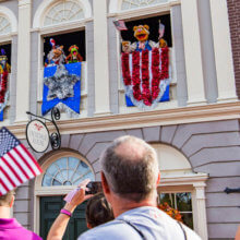 Figuren der Muppets sind in Fenstern zu sehen und Schwenken USA-Flaggen