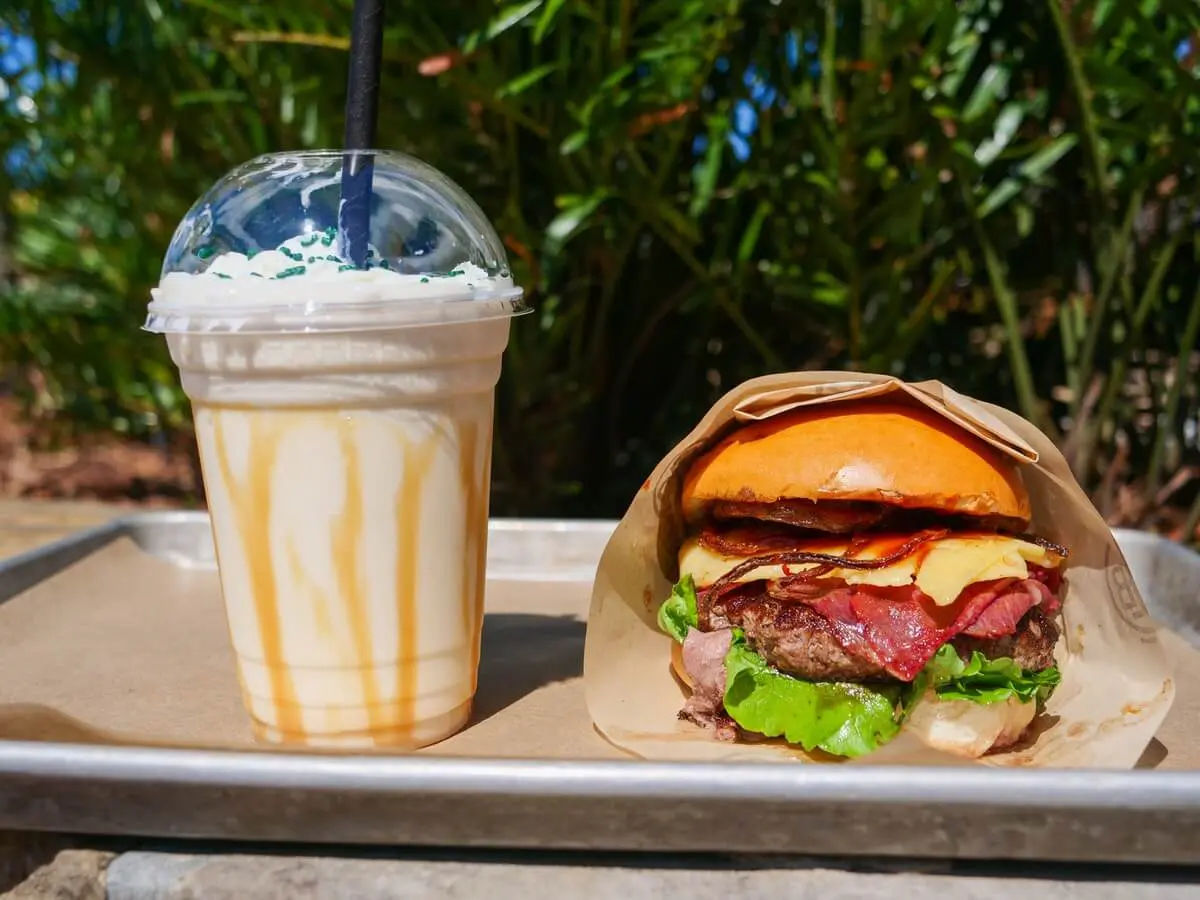 Milkshake und Burger auf einem Tablett steht ein Shake in einem Plastikbecher neben einem Burger