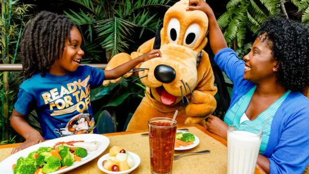 Pluto beim Essen Pluto besucht eine Mutter und ihren Sohn an einem Tisch im Restaurant Garden Grill in Epcot