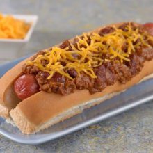 Auf einem Tresen steht ein Hotdog mit üppigem Belag