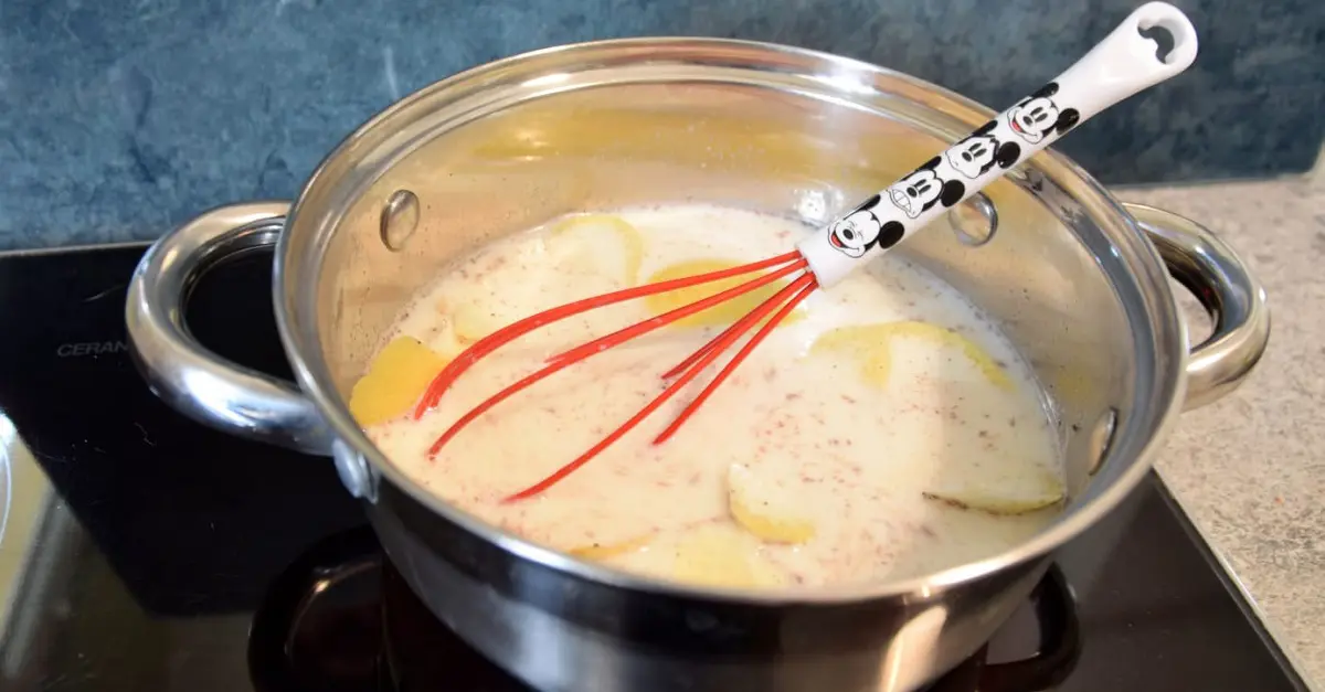 Auf dem Herd steht ein kleiner Topf mit Milch und den Gewürzen zur Zubereitung der Crema Catalana