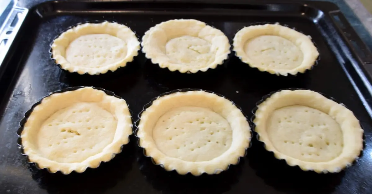 Vorgebackene Tarteletts Auf einem Backblech liegen sechs vorgebackene Tarteletts