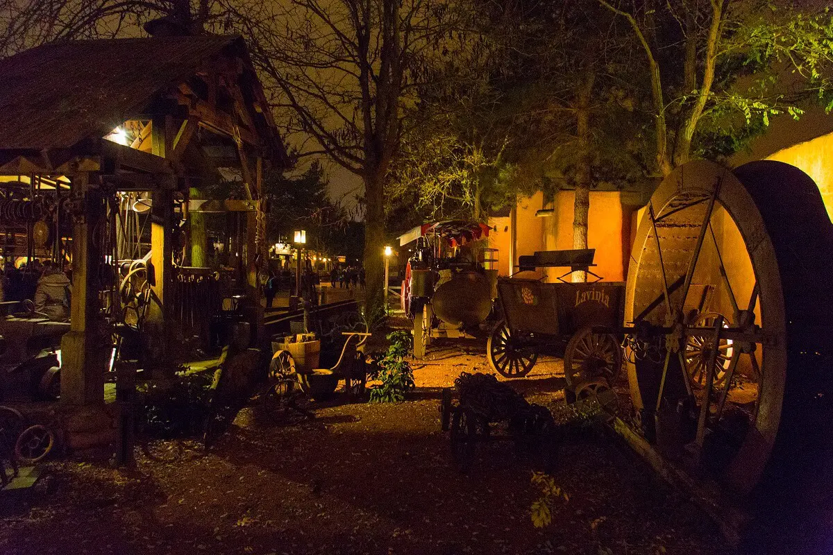 Frontierland Deko bei Dunkelheit Ein Blick auf die Dekoration des Frontierland am Wegesrand mit alten Arbeitsmaschinen, hölzernen Pavillons und karger Vegetation.