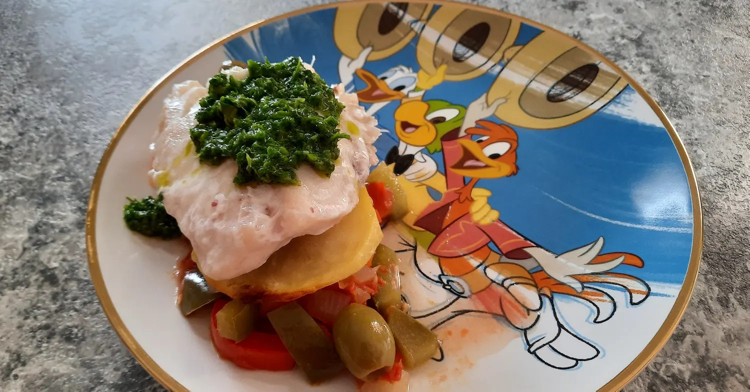 Eine Portion des Pescado a la Veracruzana nach einem Rezept aus dem San Angel Inn Restaurante auf einem Teller mit Drei Caballeros-Motiv