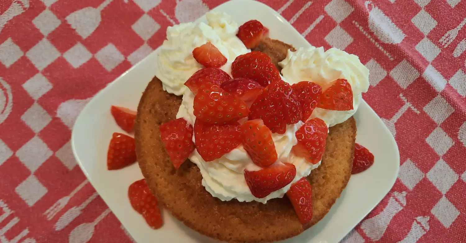 Shortcake mit Erdbeeren und Sahne Ein kleiner Shortcake mit Sahne und Erdbeerstücken ist hübsch auf einem kleinen Teller angerichtet