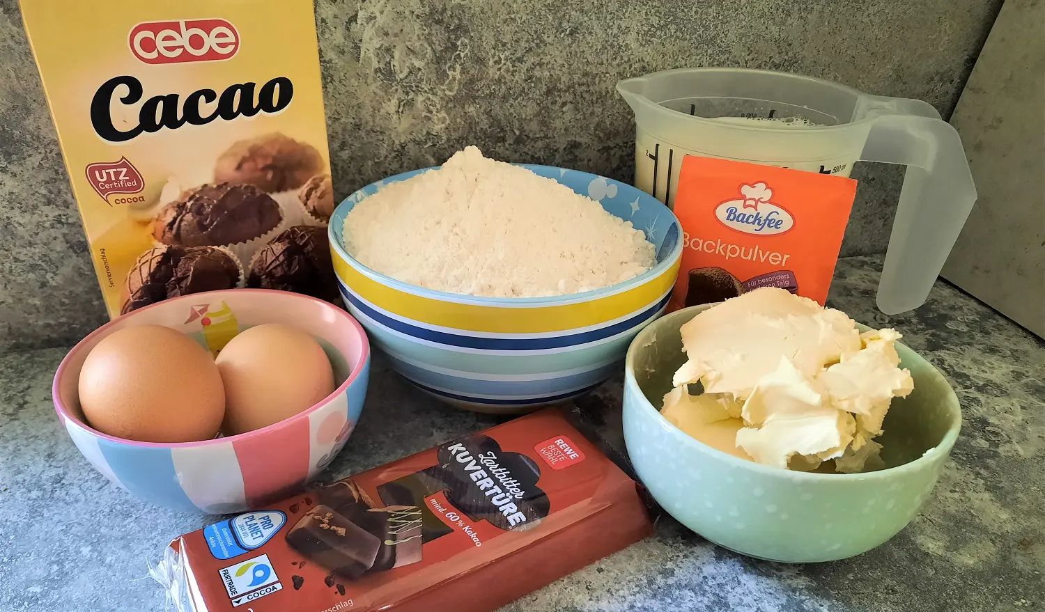 Zutaten für die Schokoladenwaffel In mehreren Schälchen und Verpackungen sind die für die Schokoladenwaffeln benötigten Zutaten sichtbar