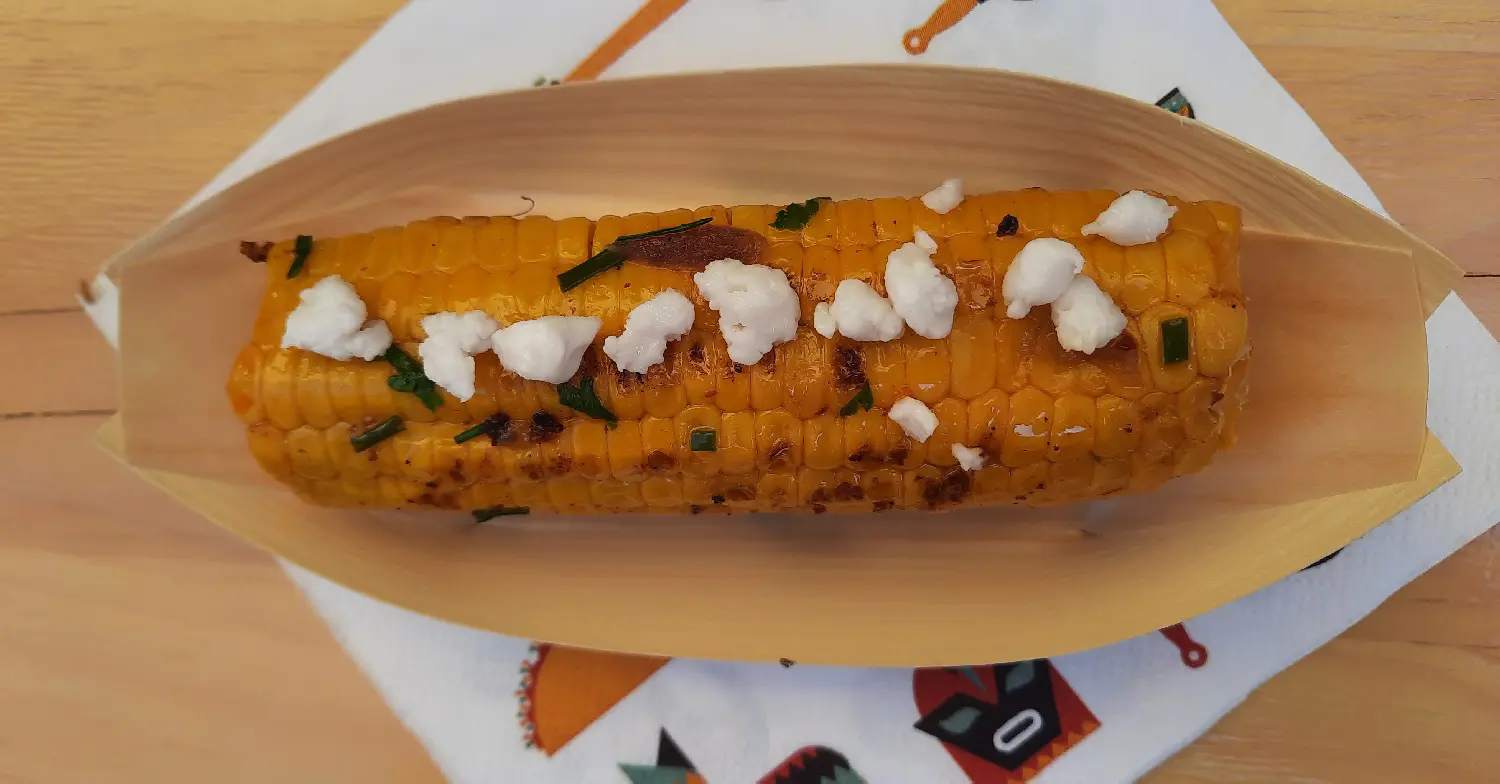 Gegrillter Maiskolben In einer Bambusschale liegt ein gegrillter Maiskolben mit Bröseln von veganem Feta obenauf
