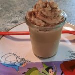 Ein Dessertglas mit Kaffee-Karamell-Dessert auf einem Teller mit Abbildung der drei Feen aus Dornröschen