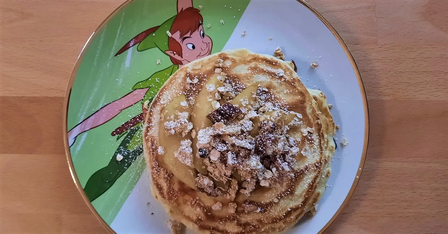 Apfel-Pancakes Pancakes mit Apfelspalten und Granola auf einem Teller mit Peter Pan-Motiv