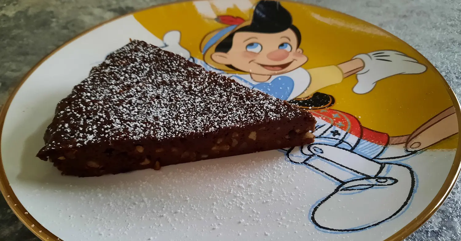 Schokoladenkuchen auf Pinocchio-Teller Ein Stück Schokoladen-Haselnuss-Kuchen auf einem Teller mit Pinocchio-Motiv
