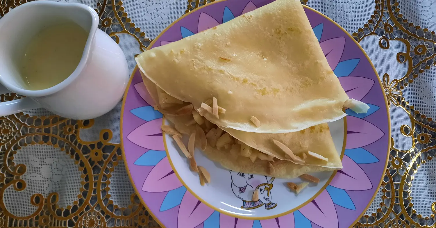 Zusammengeklappter Crepe Auf einem Teller mit Die Schöne und das Biest Motiv liegt ein Crepe mit Apfelfüllung