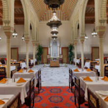Gastraum des Restaurant Marrakesh mit Tischen und Stühlen sowie einer großen freien Fläche im Zentrum, ober der ein riesiger Kronleuchter hängt 