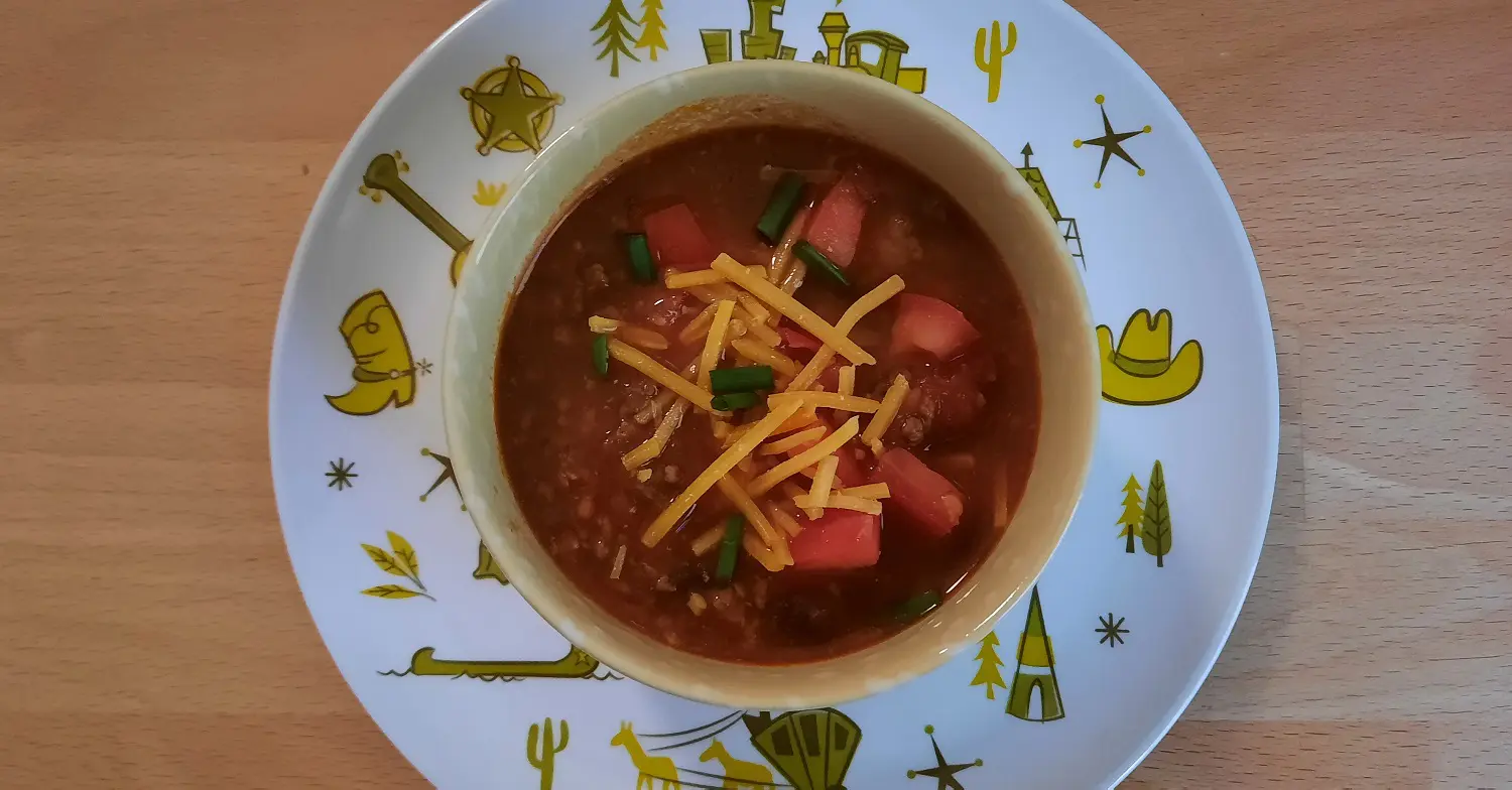 Chili mit Käse Eine kleine Schale Chili steht auf einem Teller mit Frontierland-Motiv