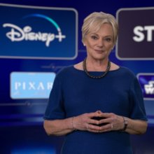 Christine McCarthy in einem dunkelblauen Kleid vor einem Bildschirm mit Disney Plus Einblendungen