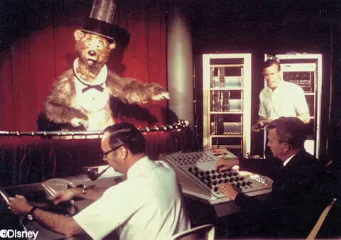 Zwei Disney Imagineers programmieren den Audio Animatronic eines Bären mit Zylinder und Fliege