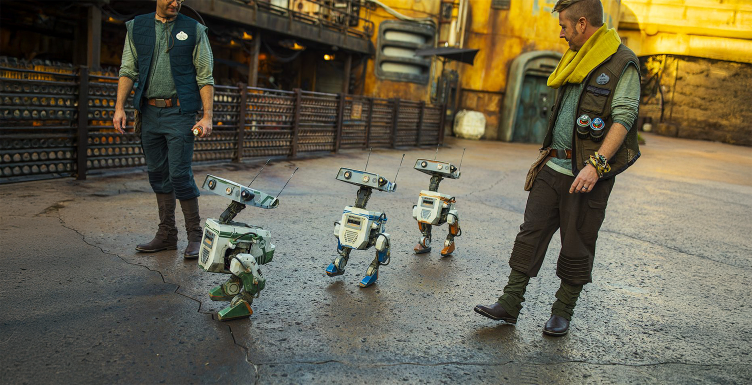 Drei BD Droids laufen mit zwei Cast Membern durch Galaxy's Edge