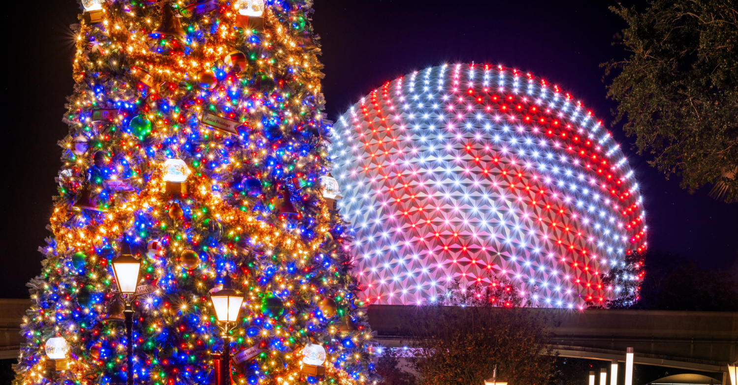 Bunt beleuchteter Weihnachtsbaum vor dem rot-weiß leuchtenden Spaceship Earth bei Dunkelheit