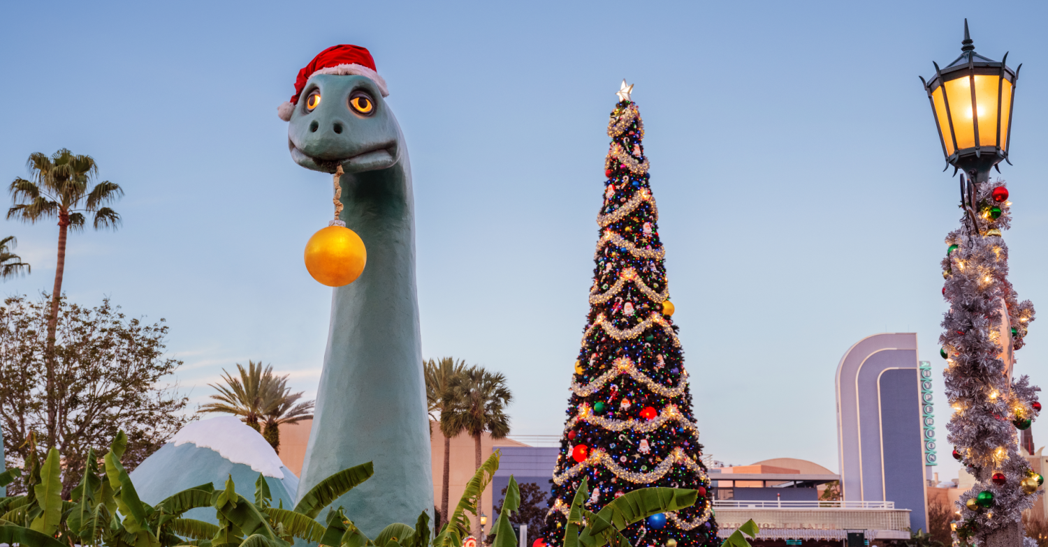 Weihnachten Hollywood Studios Gertie the Dinosaur trägt eine Weihnachtsmütze und hat eine Weihnachtsbaumkugel im Maul