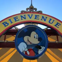 Medaillon mit einem Bild von Mickey Mouse, darüber ein geschwungener Schriftzug 'Bienvenue'
