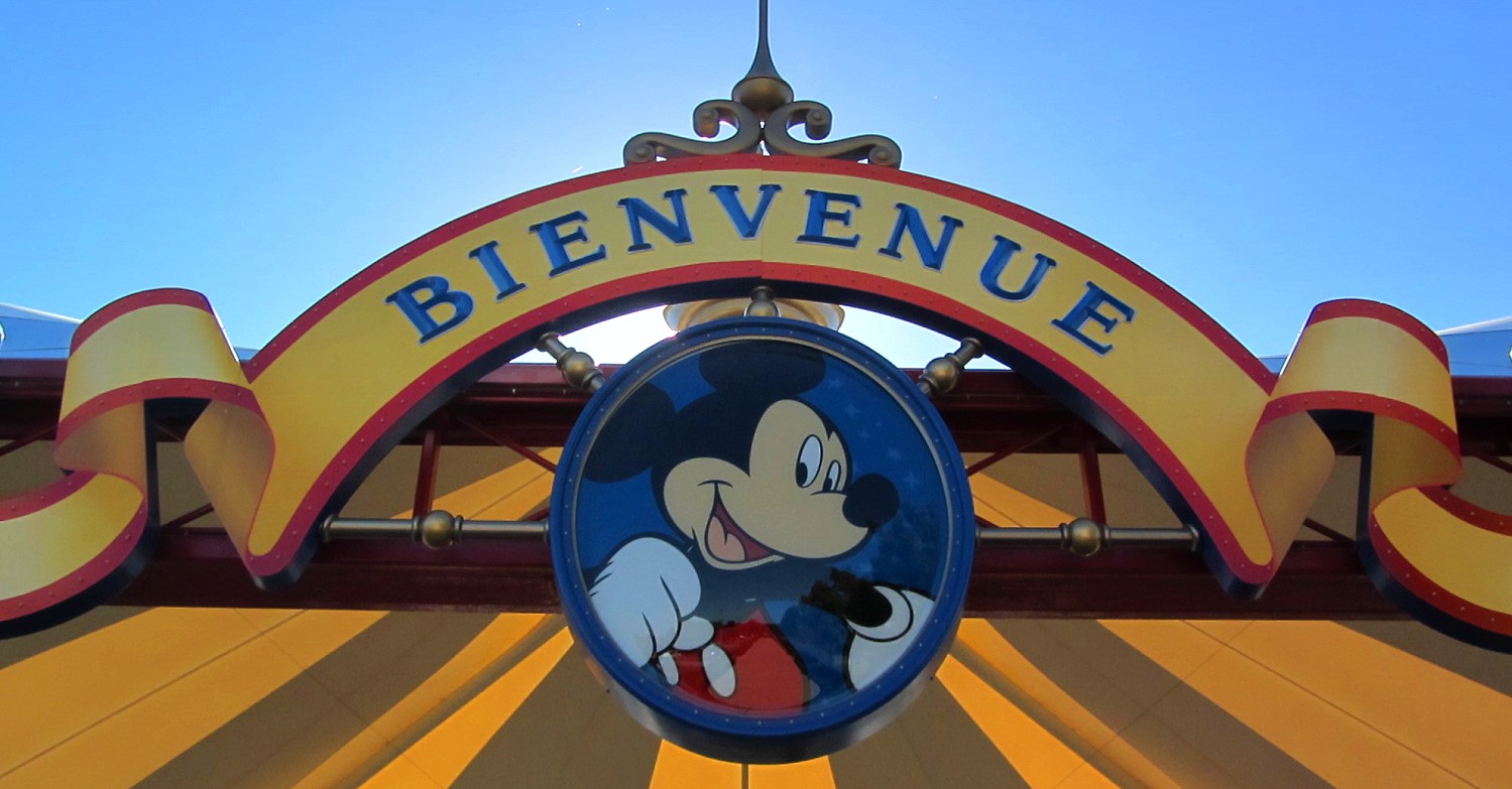 Medaillon mit einem Bild von Mickey Mouse, darüber ein geschwungener Schriftzug 'Bienvenue'