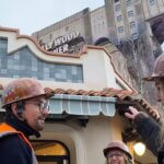 Drei Disney Imagineers mit Sicherheitshelmen und Warnwesten vor der neuen Boutique am Tower of Terror