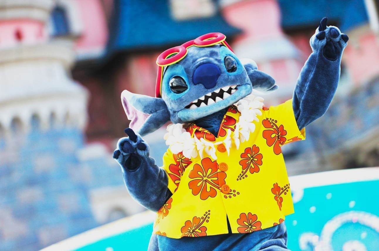 Stitch im Hawaiihemd auf der Castle Stage mit dem Sleeping Beauty Castle im Hintergrund
