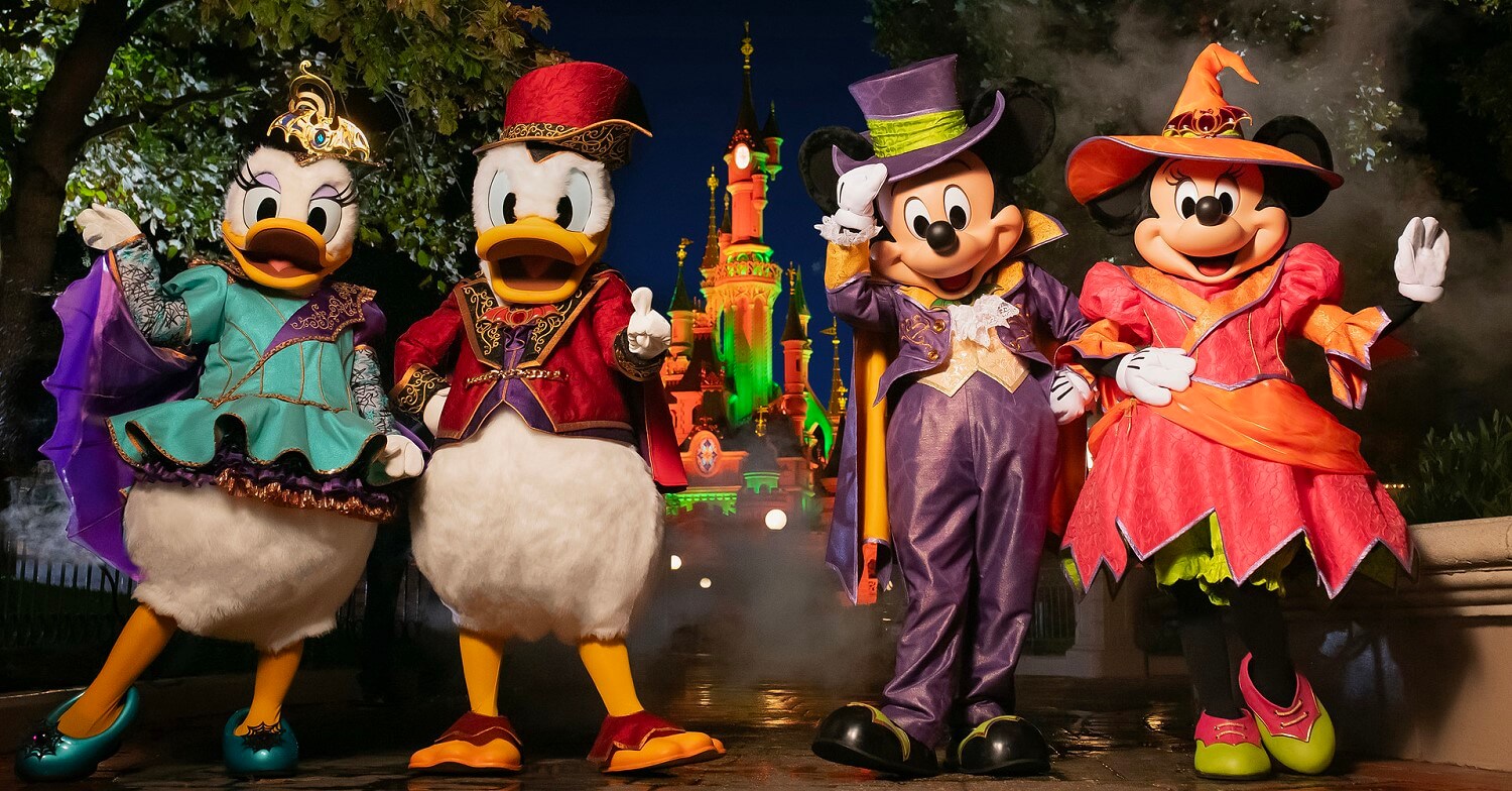 Mickey, Minnie, Donald und Daisy in Halloween Köstümen vor dem Disney Schloss