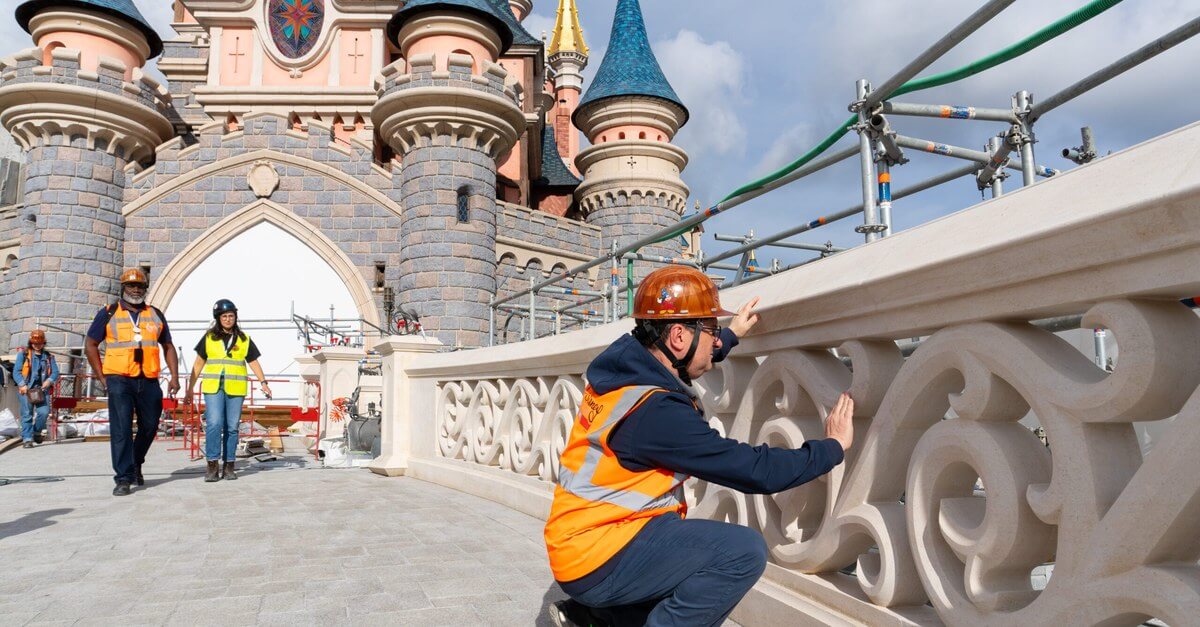 Ein Handwerker prüft die neu aufgebaute Steinbalustrade der Brücke vor dem Dornröschenschloss in Disneyland Paris