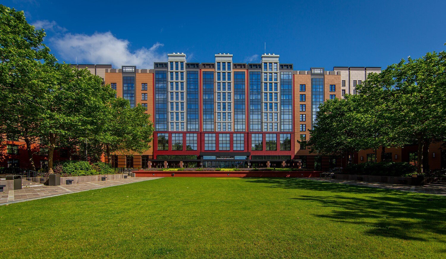 Außenansicht Hotel New York The Art Of Marvel Blick vom Lake Disney auf das Hotel mit Grünfläche im Vordergrund.