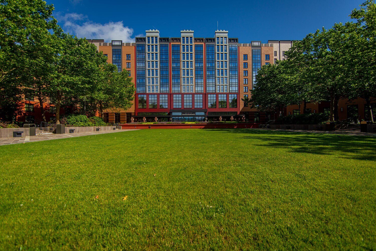 Außenansicht Hotel New York The Art Of Marvel Blick vom Lake Disney auf das Hotel mit Grünfläche im Vordergrund.
