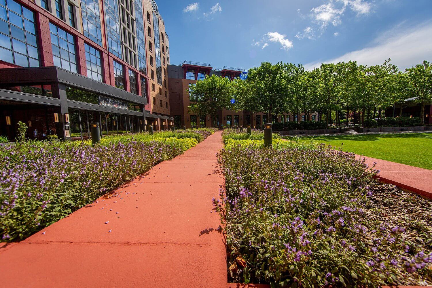 Eingangsbereich Hotel Eingangsbereich von außen. Neben den Wegen sind Blumenbeete zu sehen.