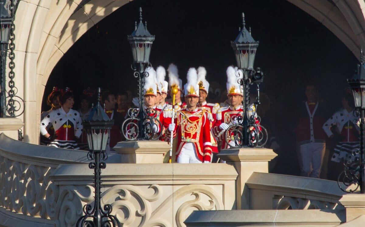 Eine Marchingband und eine Tanzgruppe sowie einige Disney Figuren haben sich unter dem Torbogen des Sleeping Beauty Castle versammelt - bereit für den Auszug in Richtung Central Plaza