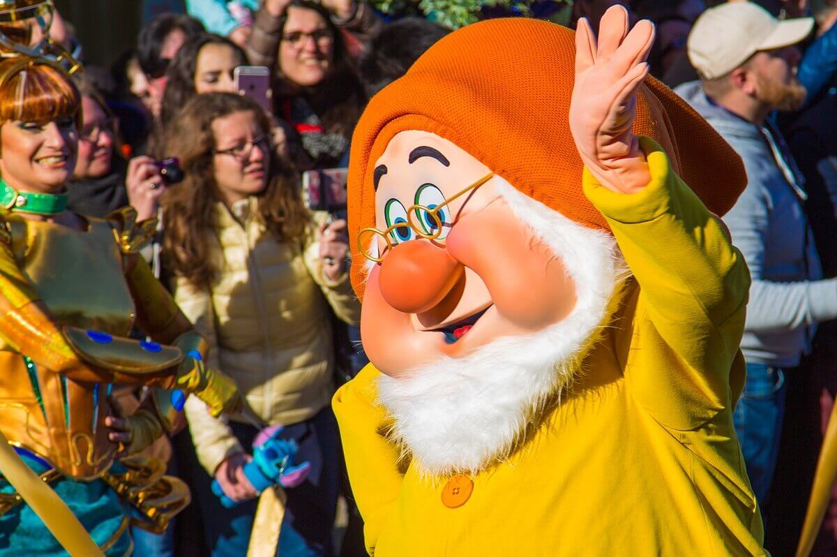 Der Zwerg Chef / Doc aus Schneewittchen läuft winkend am Publikum auf der Main Street, U.S.A. vorbei
