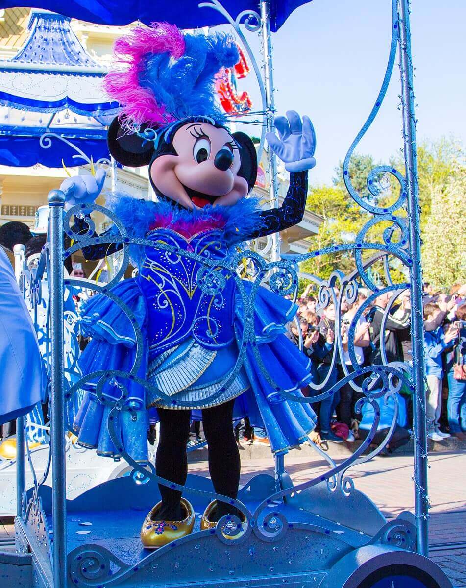 Minnie Mouse winkt aus dem Anhänger eines Tricycles heraus ins Publikum